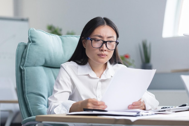 Deadlines are burningyoung beautiful asian businesswoman is worried sits in the office at the desk