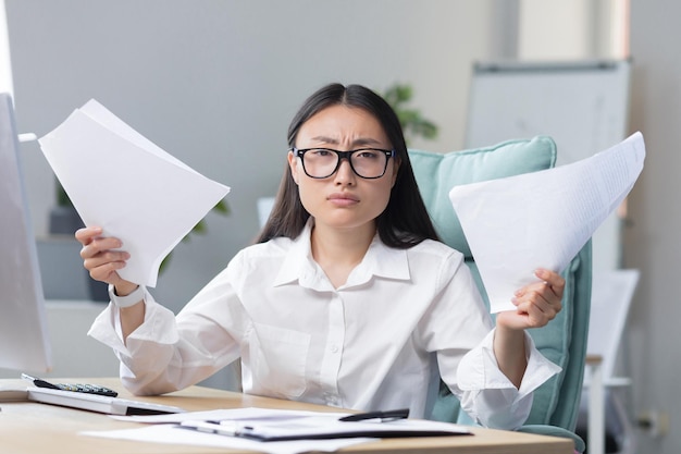 Deadlines are burningyoung beautiful asian businesswoman is worried sits in the office at the desk