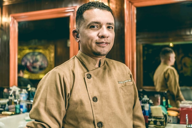 Deaf young barber with hearing aid looks at camera