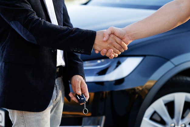 Dealer giving key to new owner in auto show or salon male hand gives a car keys to male hand