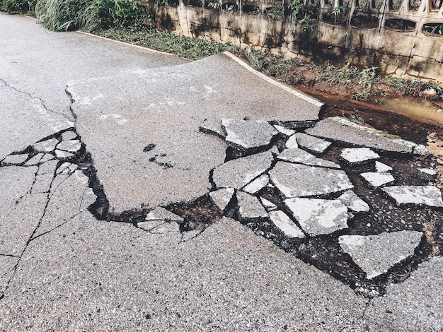 Decayed road paved asphalt distressed road surface with damaged peeling damaged road waiting for road repair roadway