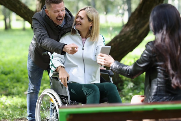 Deceased woman in wheelchair with her friends having fun while walking in park friend support