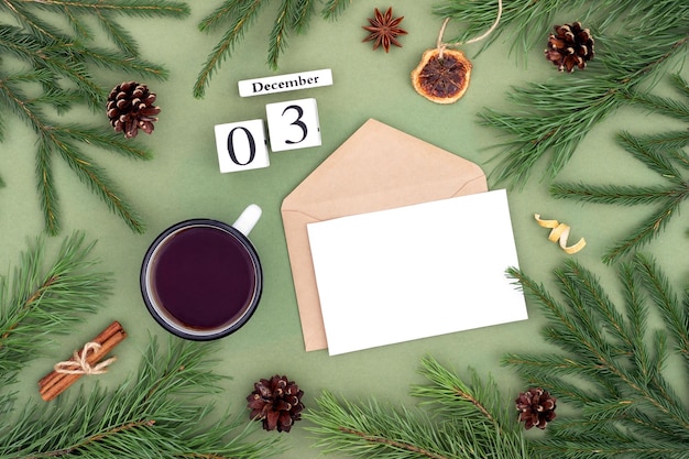 December 3 Calendar date white blank with craft envelope cup of tea and natural decor on green background Hello winter Template for your design greeting card