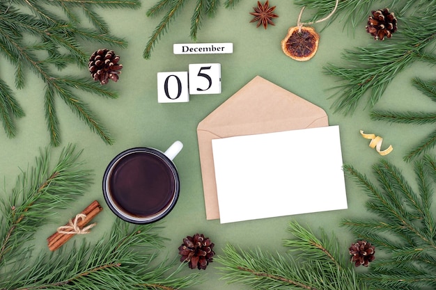 December 5 Calendar date white blank with craft envelope cup of tea and natural decor on green background Hello winter Template for your design greeting card