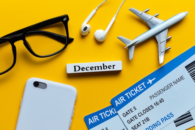 December vacation concept next to tickets and airplane model on yellow background.