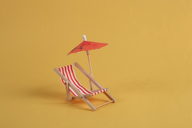 Deck chair with umbrella on a yellow background Beach rest