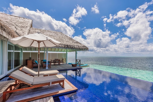 Deck chair with umbrellas at Maldives resort with infinity pool and beach, sea sky view