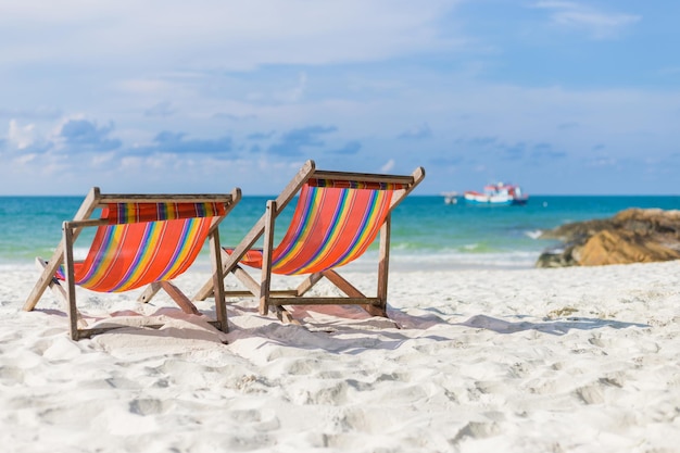 Deck chairs on beach against sky