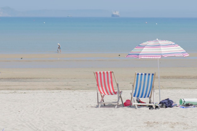 Deck chairs on beach against sky