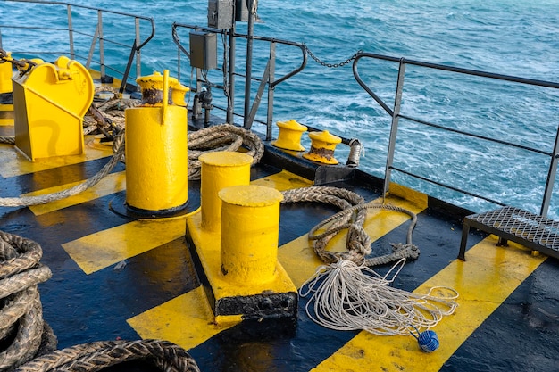 The deck of the ferry boat along with the a thick mooring rope and blue sea water wave Thailand Close up