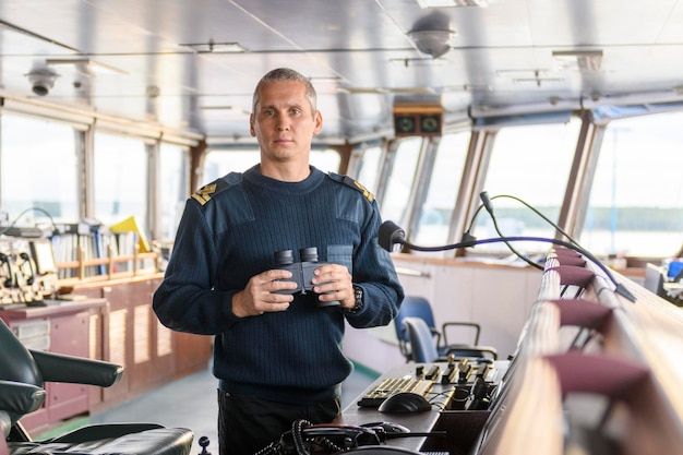 Deck officer with binoculars on navigational bridge Seaman on board of vessel Commercial shipping