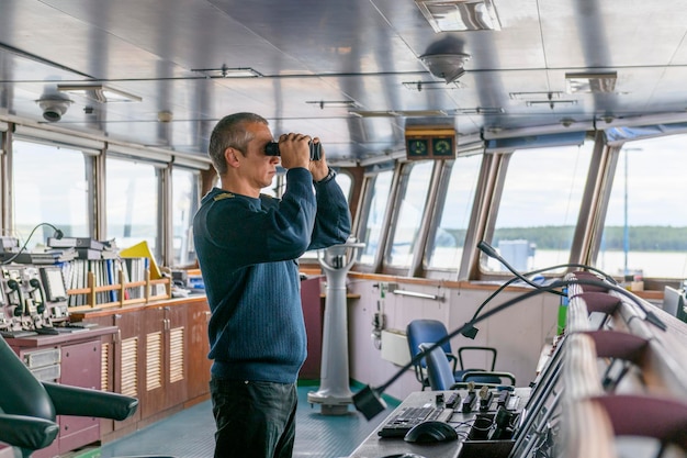 Deck officer with binoculars on navigational bridge Seaman on board of vessel Commercial shipping