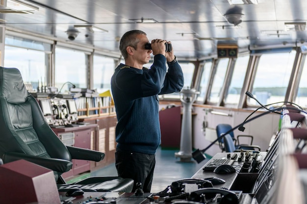 Deck officer with binoculars on navigational bridge Seaman on board of vessel Commercial shipping