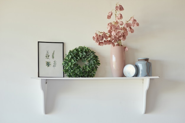 Photo decorate on your own decorative shelf on white wall with framed picture and flowers in vase on it