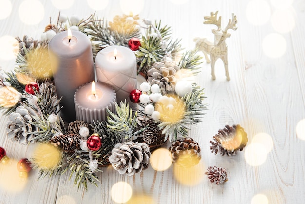 Decorated Advent wreath from fir branches with burning candles tradition in the time before Christmas White old wooden background