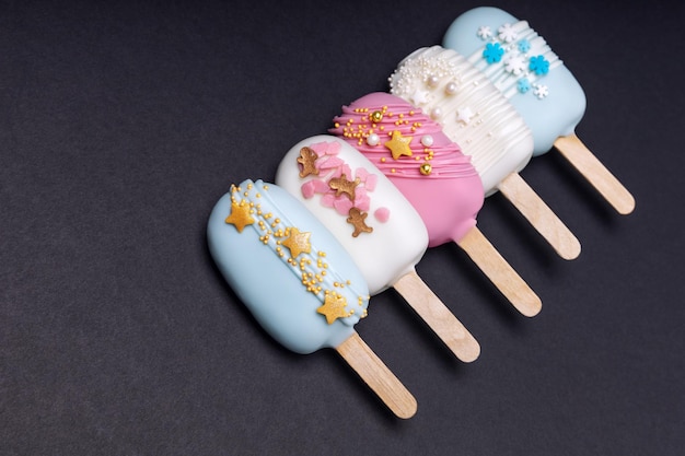 Decorated cake pops ice creams on black background