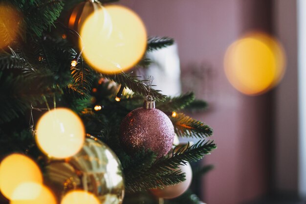 Decorated Christmas tree in gold and purple toys with the lights bokeh textured background