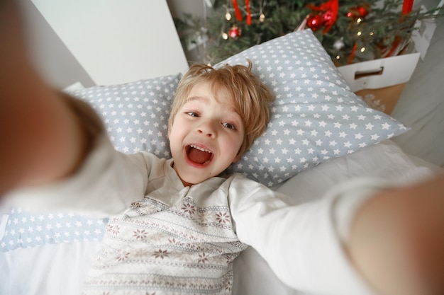 Decorated Christmas tree stands in the room near the bed on which the child lies