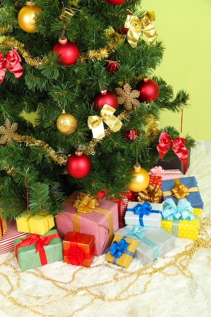 Decorated Christmas tree with gifts on green wall background