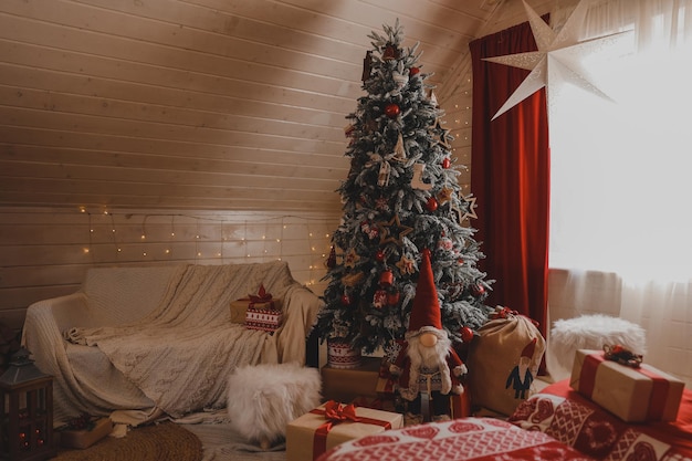 Decorated Christmas tree with gifts in white classic bedroom interior with New Year's holiday sparkling garland.