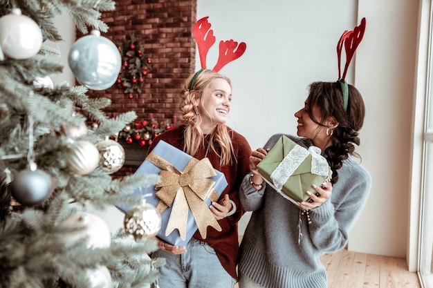 Decorated presents. Happy childish girls carrying wrapped boxes with gifts inside and dancing in festive manner Christmas concept