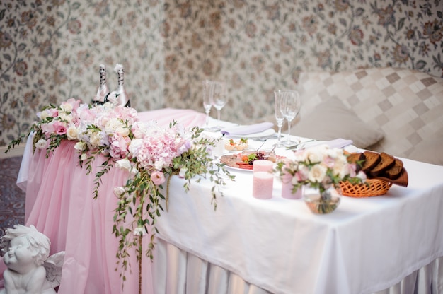 Decorated in white and pink tones wedding buffet table with dishes and champagne