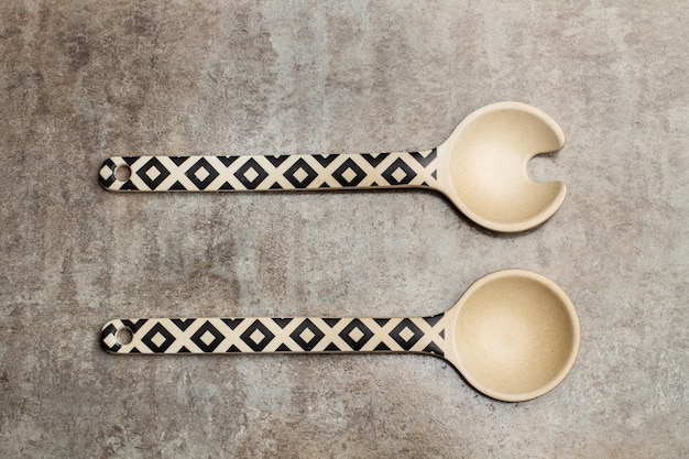 Decorated wooden salad server spoons on a marble table