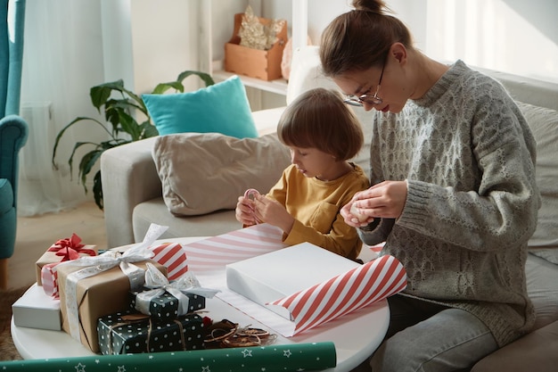 Decorating Christmas gifts family mother and child wrapping Christmas gift box together