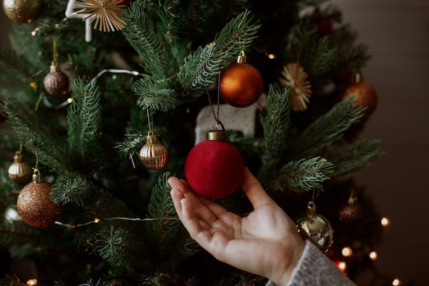 Decorating christmas tree with modern red bauble in festive decorated room Merry Christmas