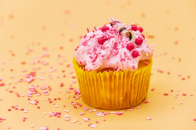 Decorating a Cupcake with Sprinkles on orange pastel background.