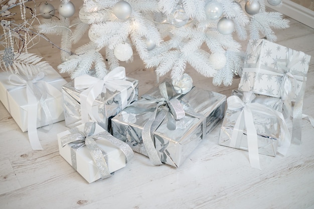 Decoration with Christmas toys and fir branches. Christmas balls in silver style and wrapped gifts