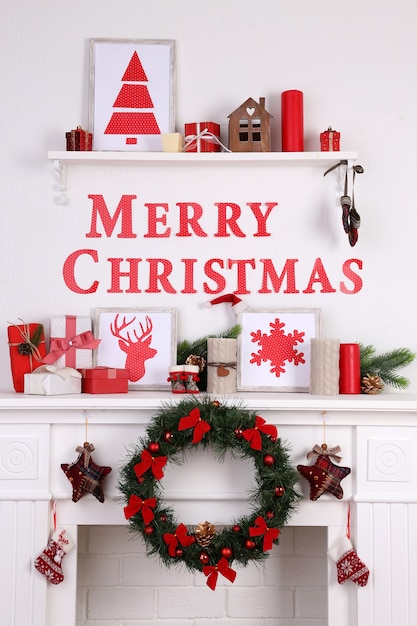 Decorations with Merry Christmas inscription on mantelpiece on white wall background