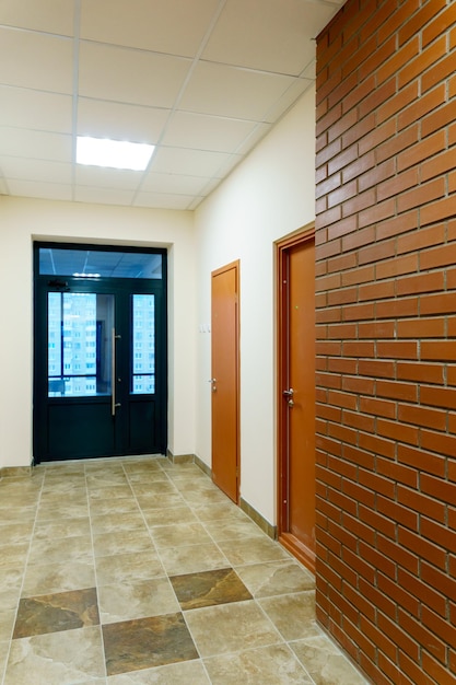 Decorative brick on the corridor wall in an office building A black glass door at the end of the corridor of the business center Interior design in the Art Nouveau style