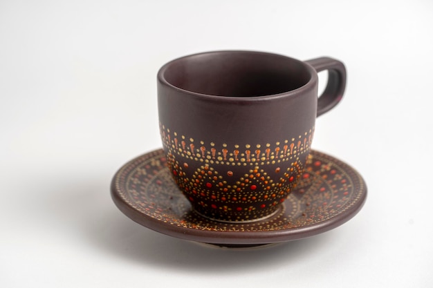 Decorative ceramic painted cup and saucer on white background close up