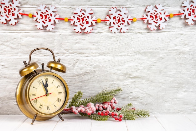 Decorative Christmas tree and alarm clock on white brick wall background