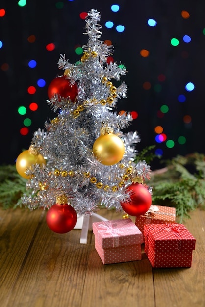 Decorative Christmas tree with gifts on table on bright background