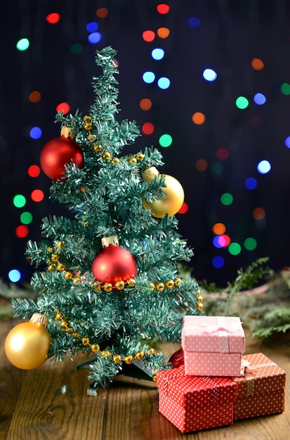 Decorative Christmas tree with gifts on table on bright background