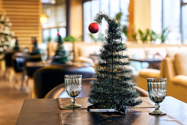 Decorative Christmas tree with red ball and goblets on table