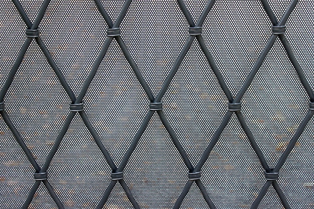 Decorative city fence with small holes and crossed metallic stripes