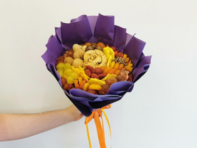 Decorative composition in the form of a bouquet of dried fruits and nuts on a white background