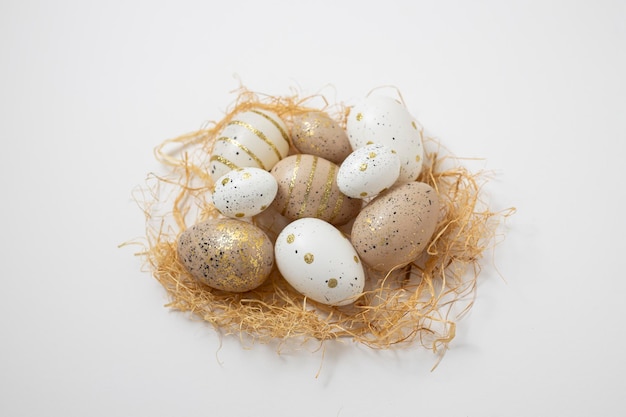 Decorative Easter eggs and straw on a white background