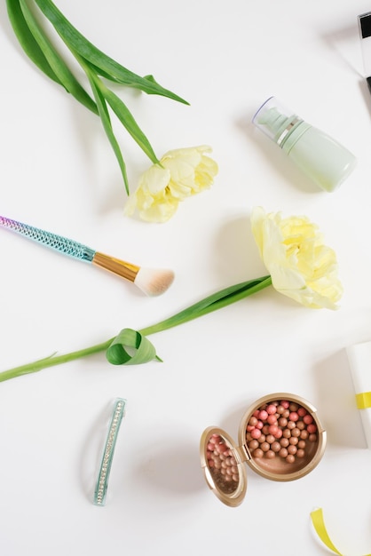 Decorative flatlay composition with make up products cosmetics and flowers Flat lay top view on white background