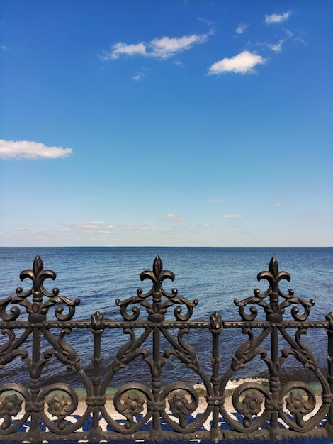 Decorative forged metal fence on the seashore near a tiled sidewalk