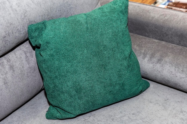 Decorative green pillow on a gray sofa Cozy and comfortable atmosphere in the design of the room Closeup