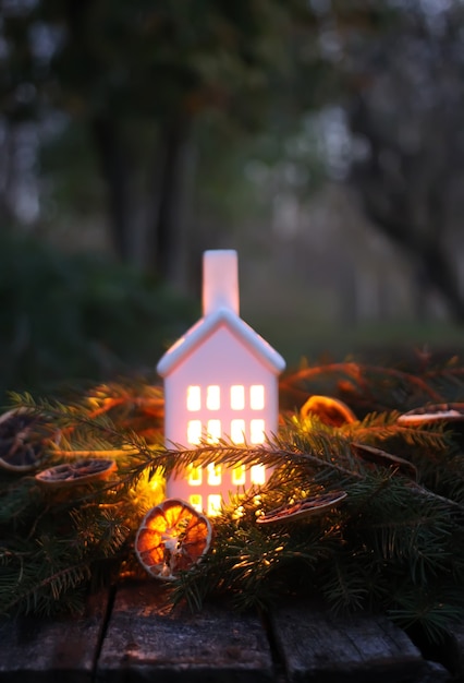 Decorative house lantern with burning candle in autumn park at evening.