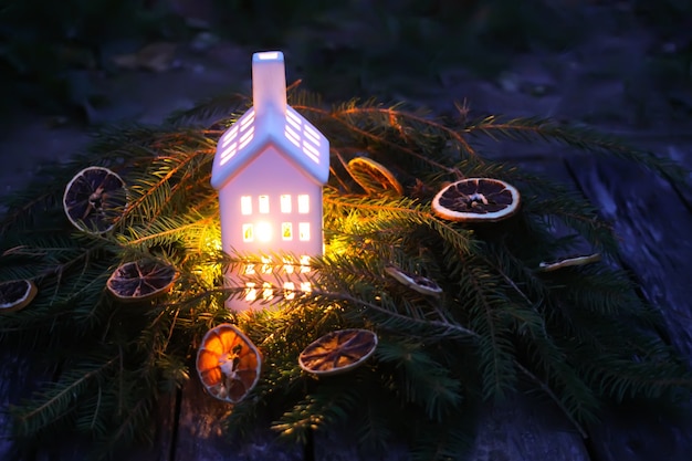 Decorative house lantern with burning candle in autumn park at evening.