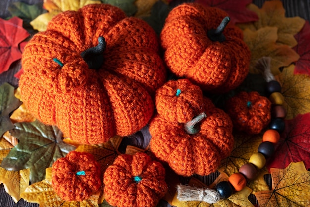 Decorative knitted pumpkins of different sizes top view Against the background of autumn multicolored leaves