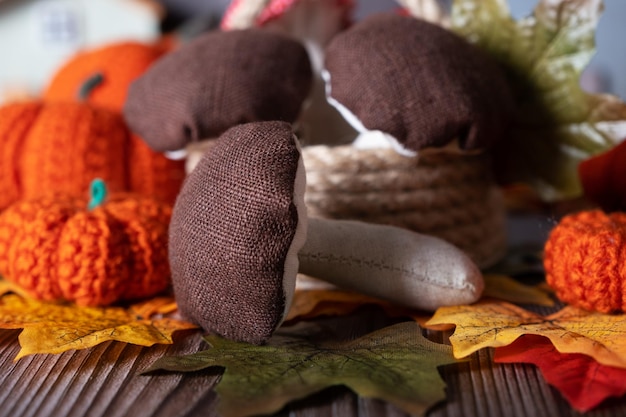 Decorative mushrooms sewn from fabric a toy for children in autumn against the background of autumn leaves and knitted pumpkins selective focus