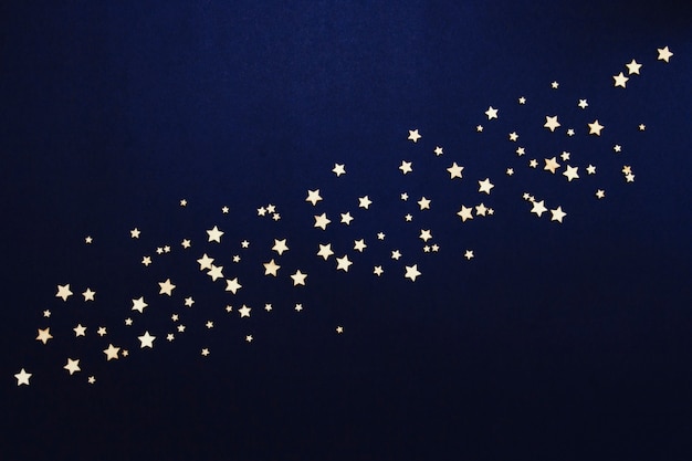 Decorative stars on a dark blue. Concept of the night sky. Can be used as wallpaper or background. Flat lay, top view