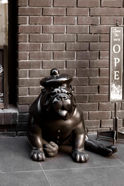 Decorative statue of cute bulldog breed dog sitting near outdoor cafe enter